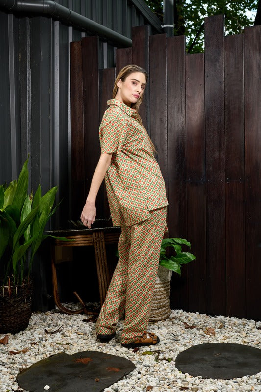 international fashion model Emma Lucille wearing a men's style pants and matching short sleeve shirt in soft organic cotton with an earthly green and orange geo pattern by Australian fashion label Analia, launched in 2023